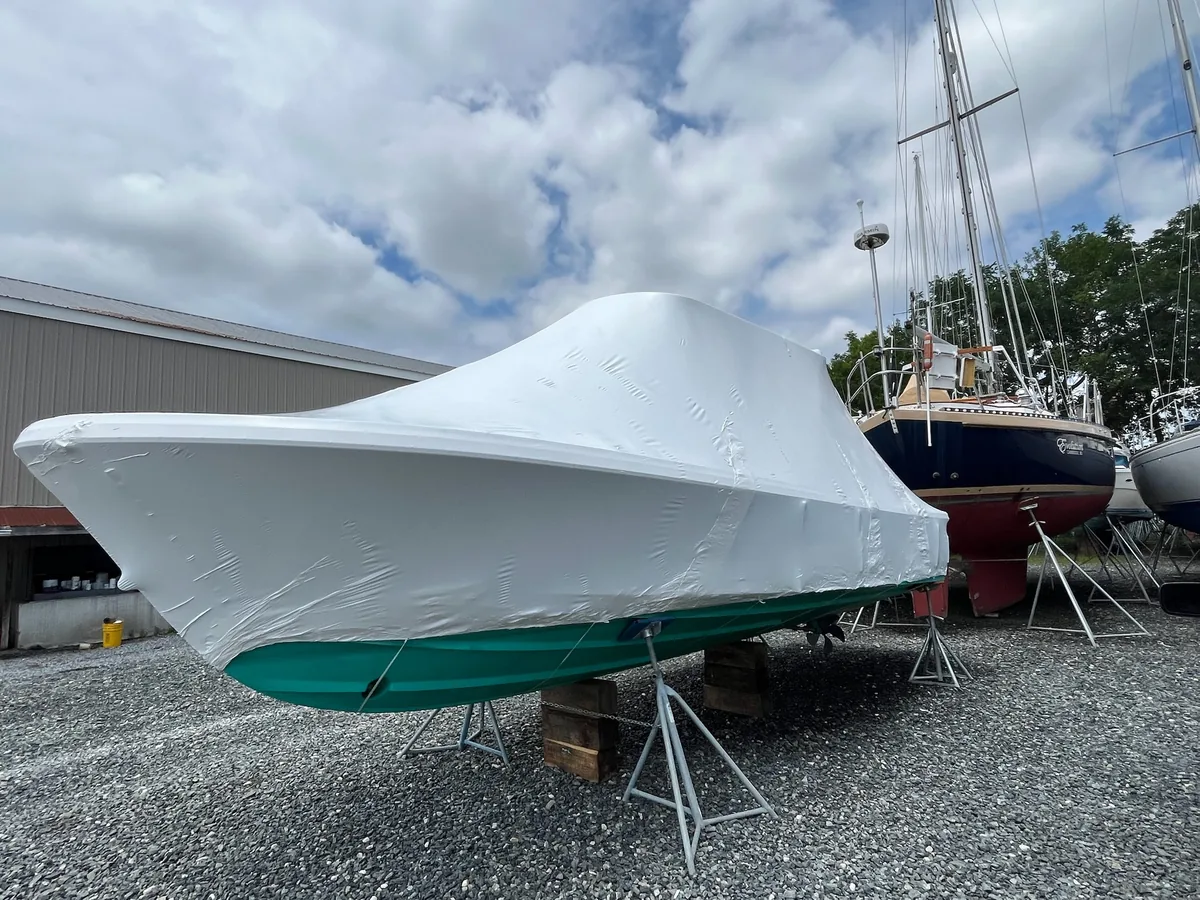 White shrink-wrap covering a powerboat on boatyard stands