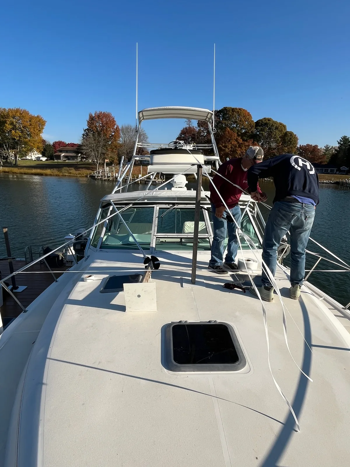 Two workers preparing support framing and straps on a boat at the dock