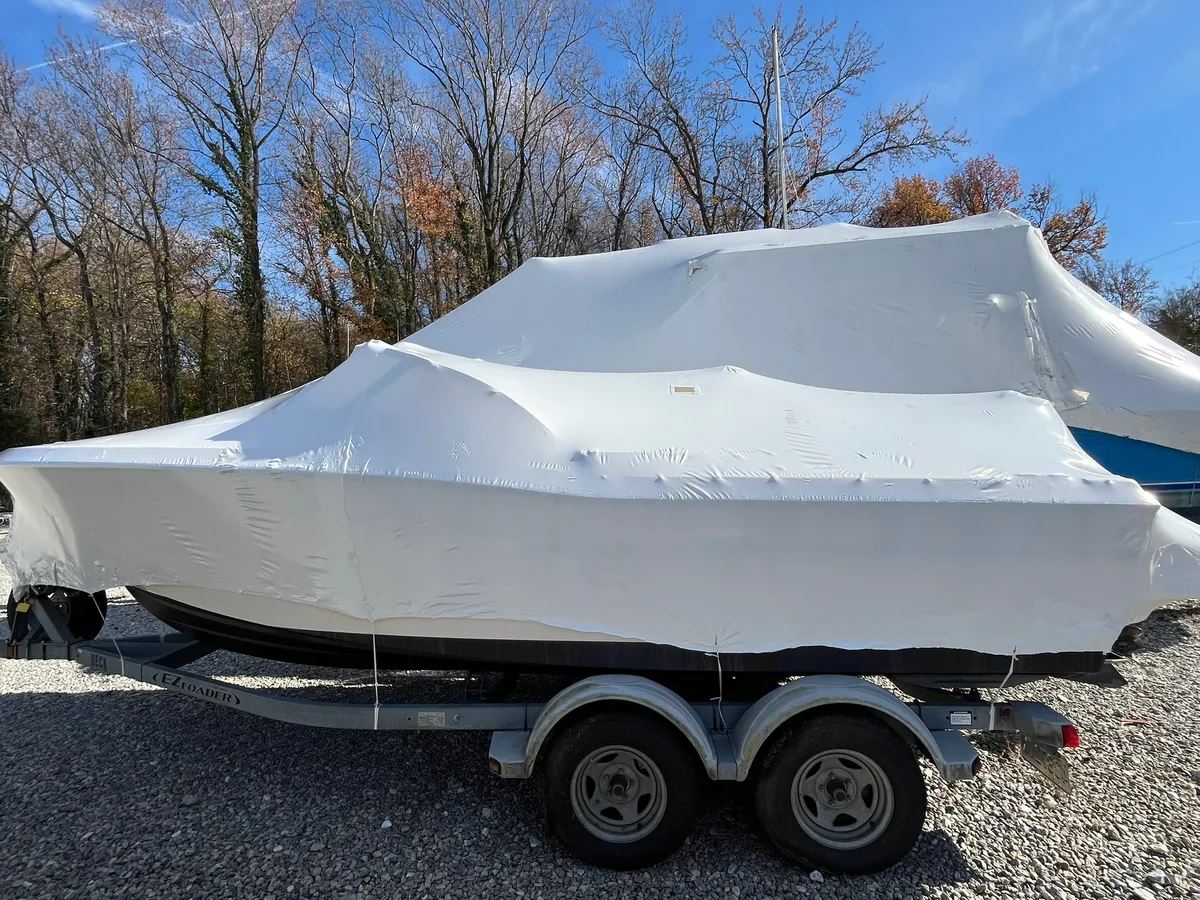 Shrink-wrapped powerboat resting on a tandem-axle trailer